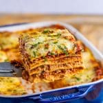 Metal server holding up one slice of lasagna out of pan.