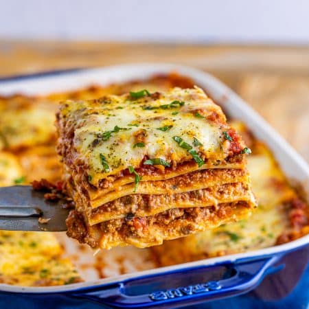 Metal server holding up one slice of lasagna out of pan.