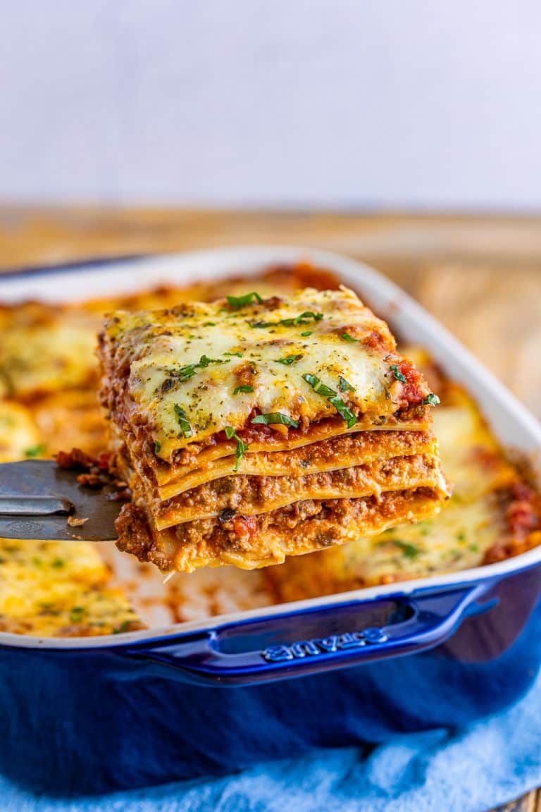 Metal server holding up one slice of lasagna out of pan.