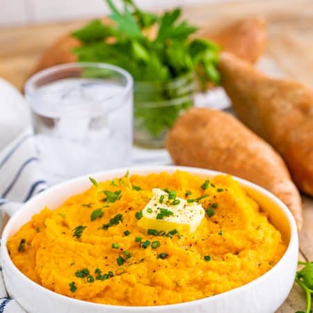 Savory Mashed Sweet Potatoes in white bowl with garnishes.