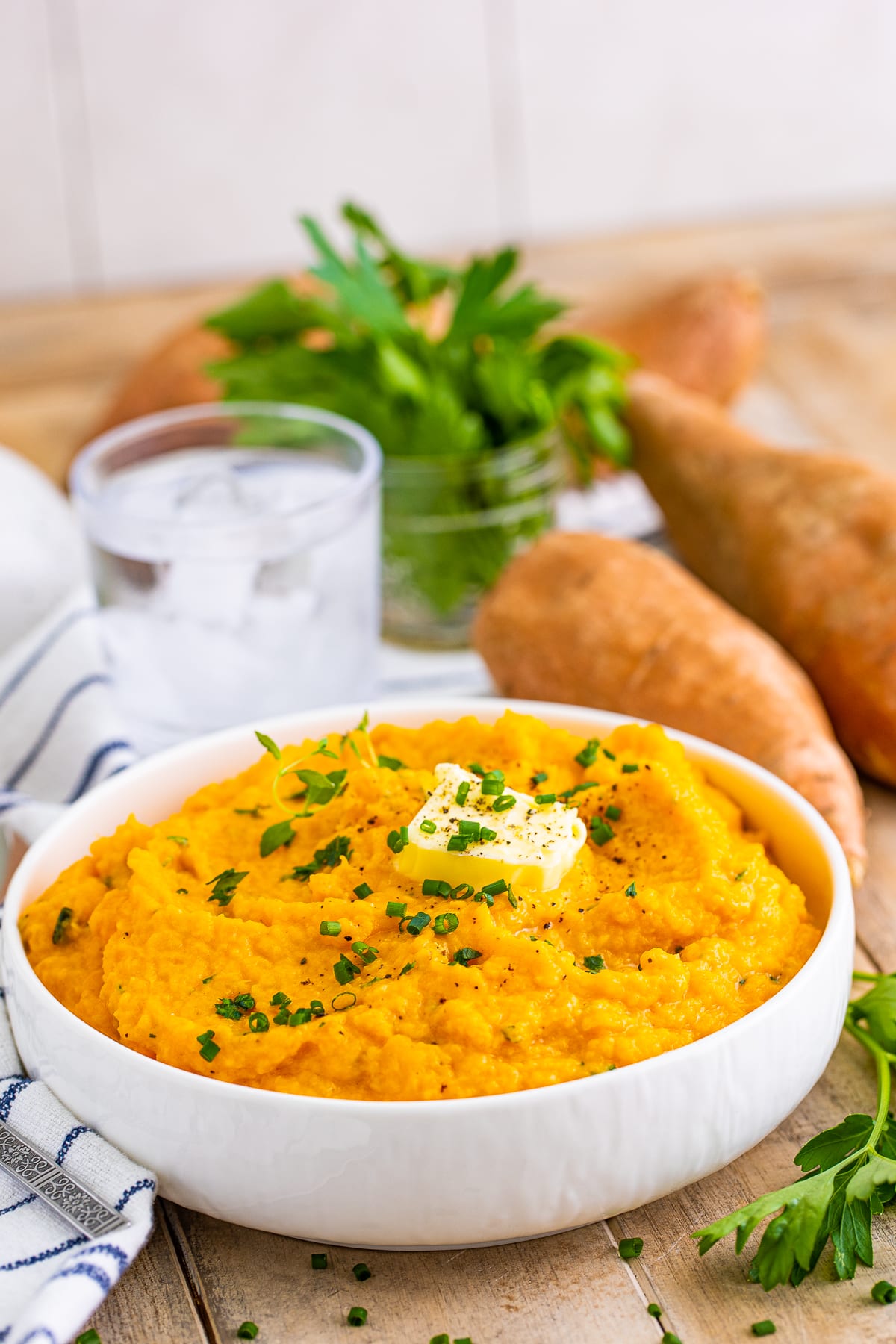 Savory Mashed Sweet Potatoes in white bowl with garnishes.