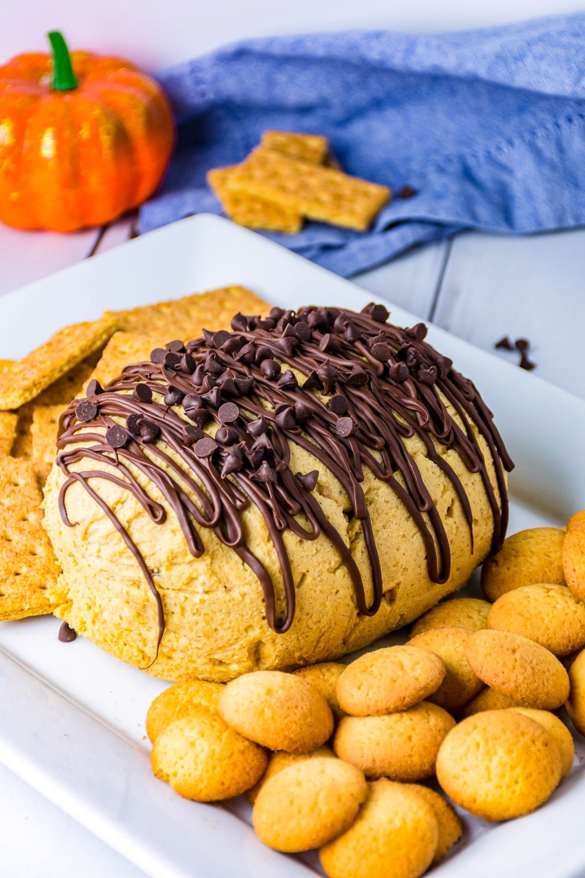 Finished Pumpkin Cheese Ball on white platter topped with chocolate and chocolate chips.