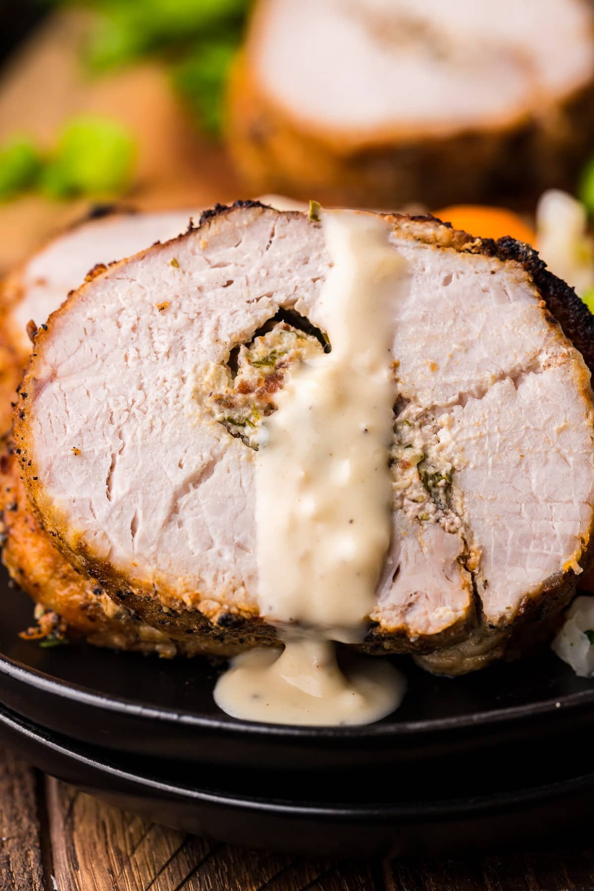 Sliced and plated Stuffed Pork Loin with sauce drizzled over.