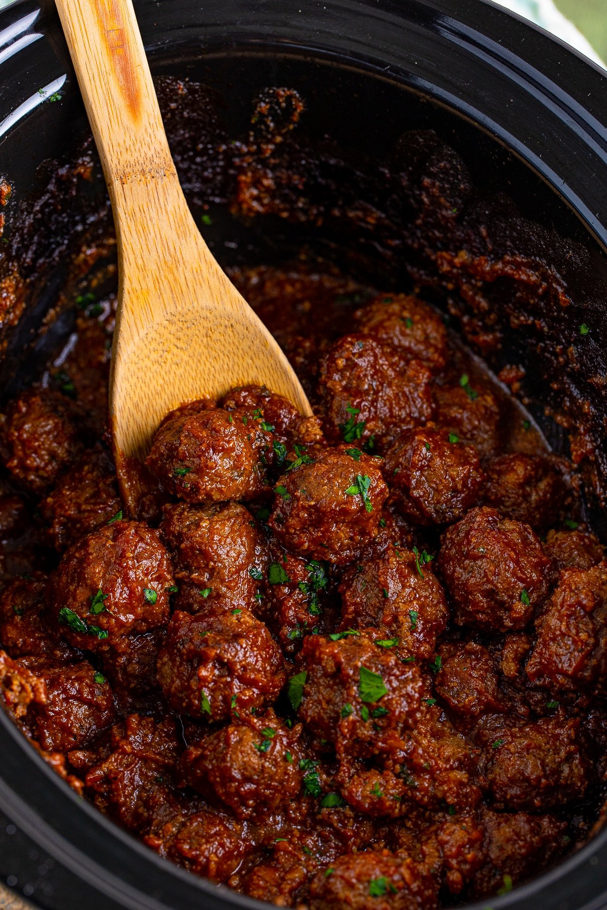 Cranberry Meatballs in slow cooker with serving spoon.