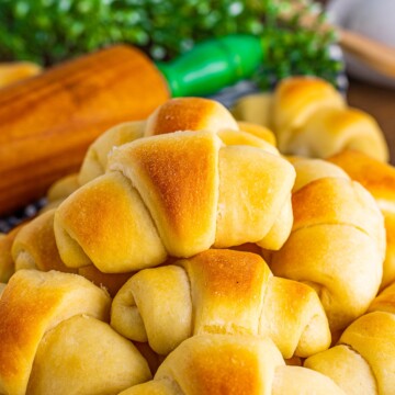 Homemade Crescent Rolls stacked on wooden platter.