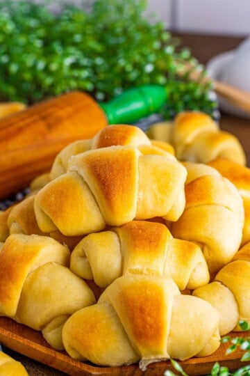 Homemade Crescent Rolls stacked on wooden platter.