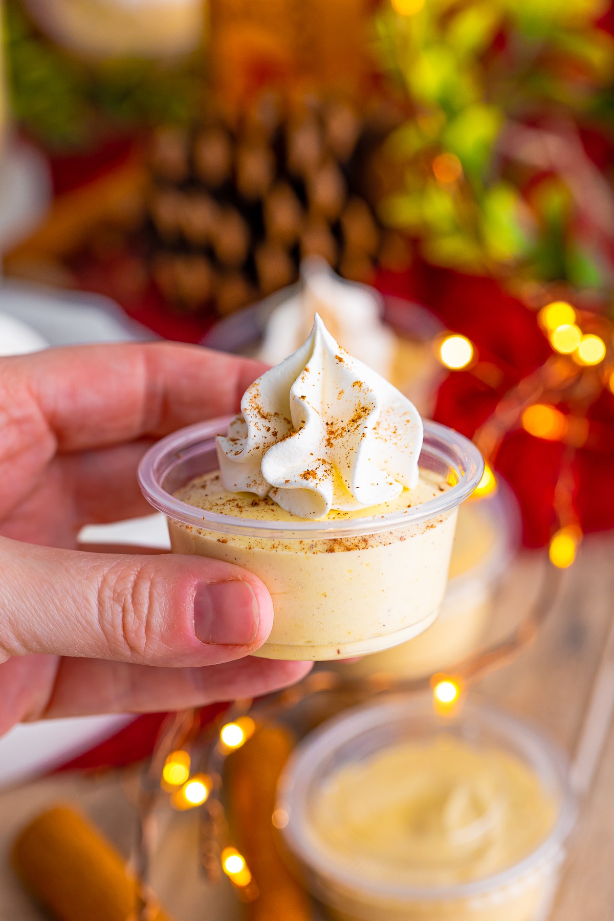 Hand holding up one of the Eggnog Pudding Shots.