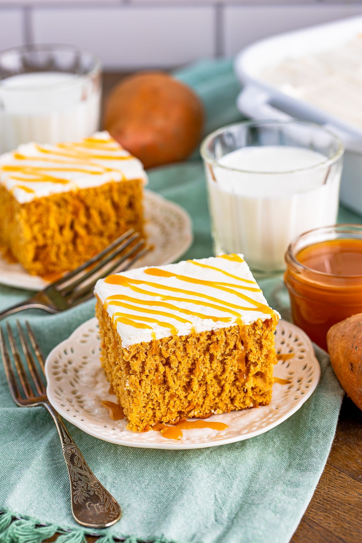 Top slices of Sweet Potato Cake on plates with caramel sauce and milk in background.