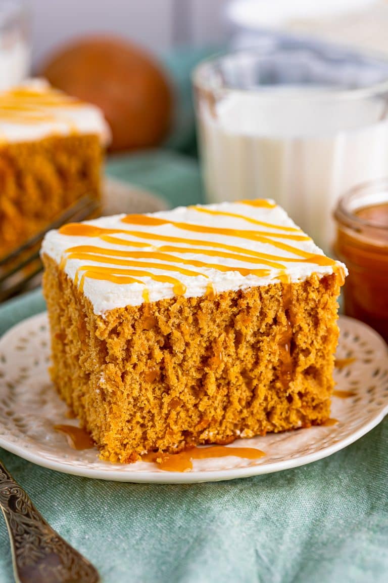 Close up of one slice of Sweet Potato Cake on white plate drizzled in caramel sauce.