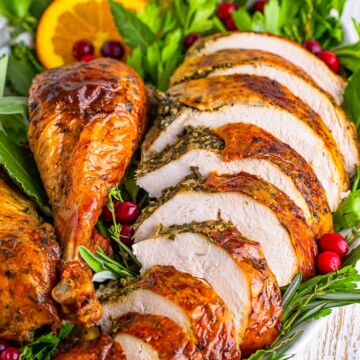 Cut up slices and pieces of the turkey on platter with garnishes.