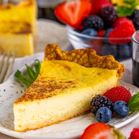 Slice of Custard Pie on white plate with fruit.