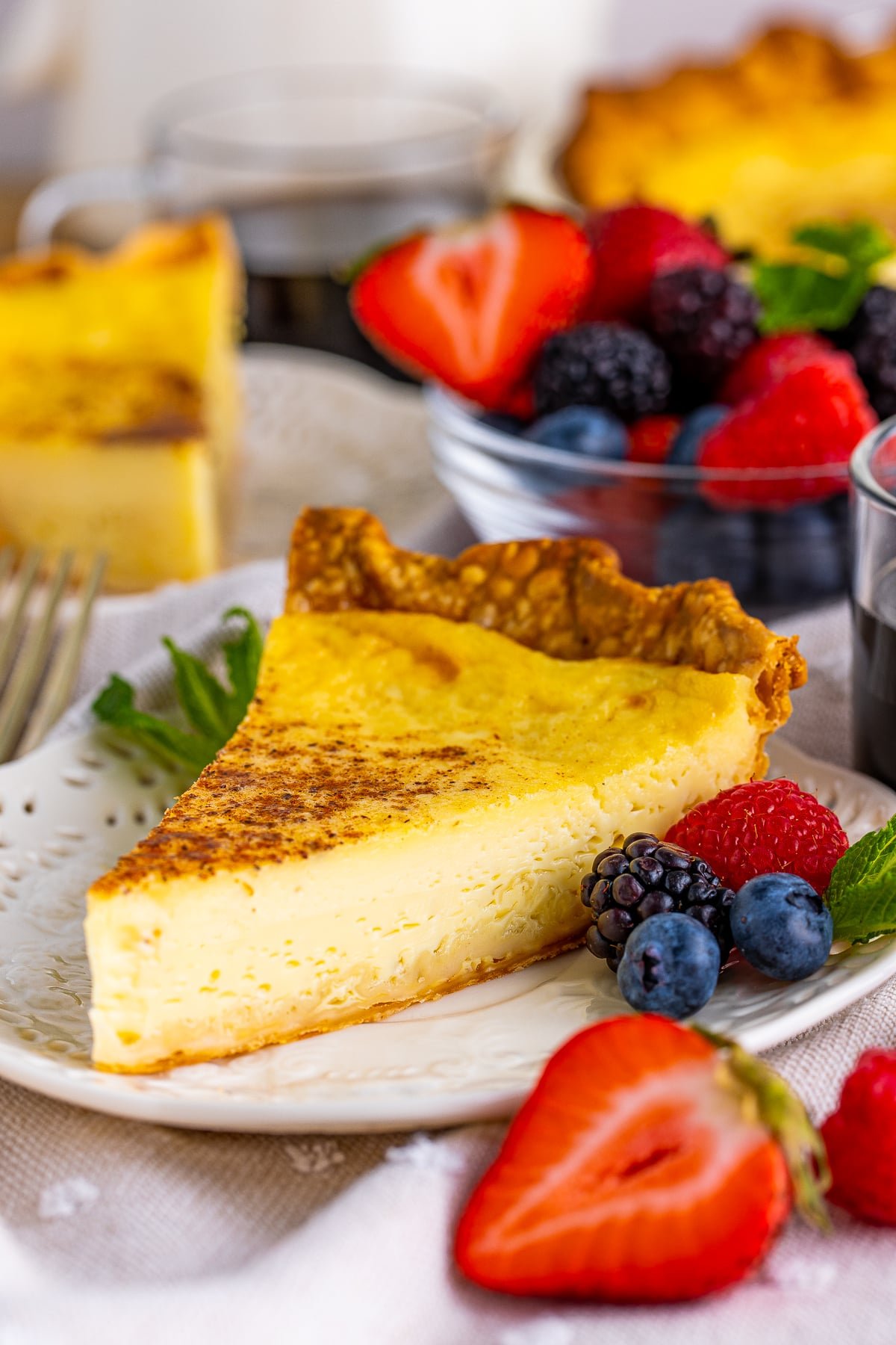 Slice of Custard Pie on white plate with fruit.