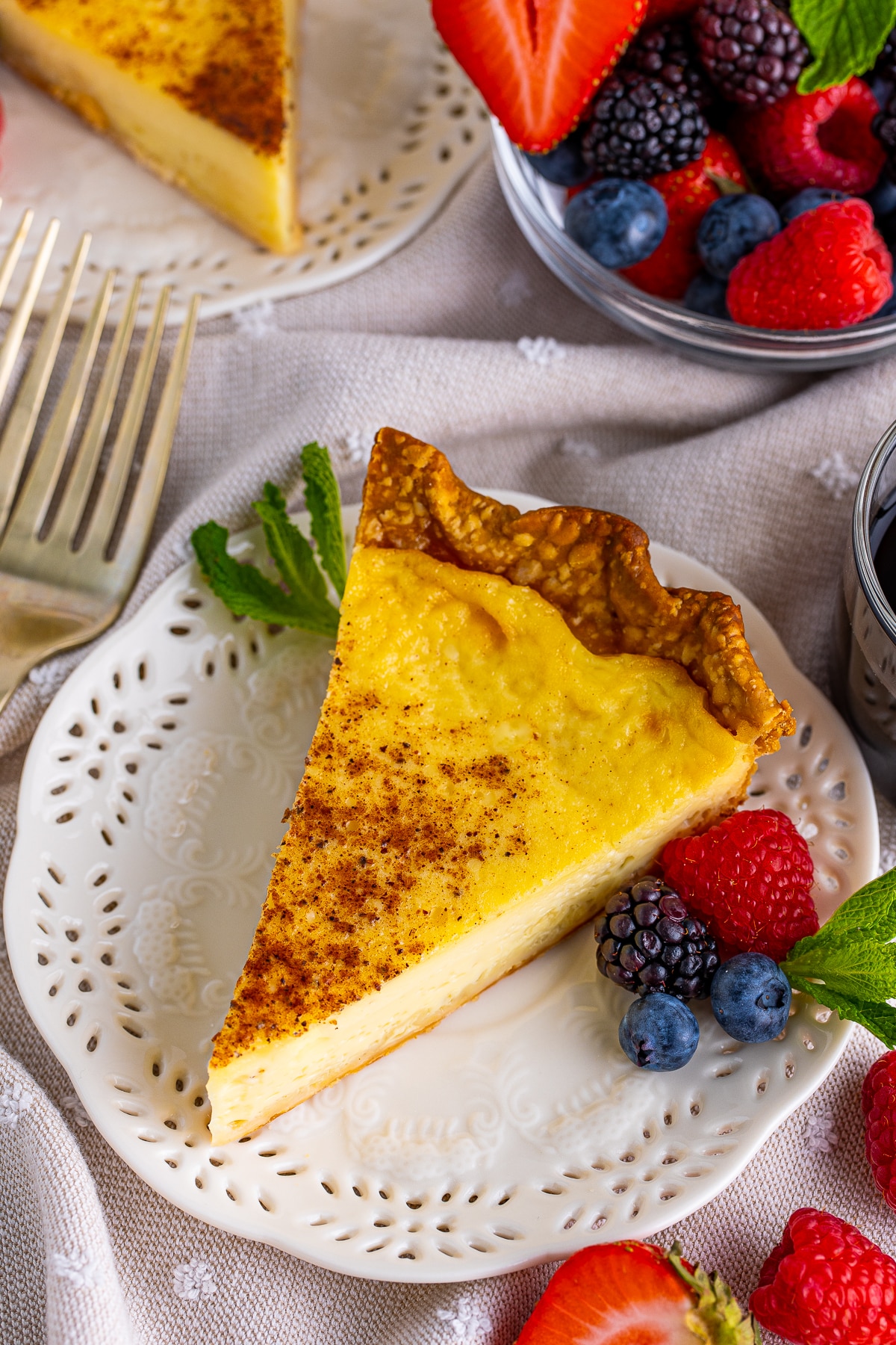 Overhead of slice of Custard Pie on white plate with fruit.