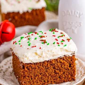 Slice of Gingerbread Cake on white plate topped with sprinkles.