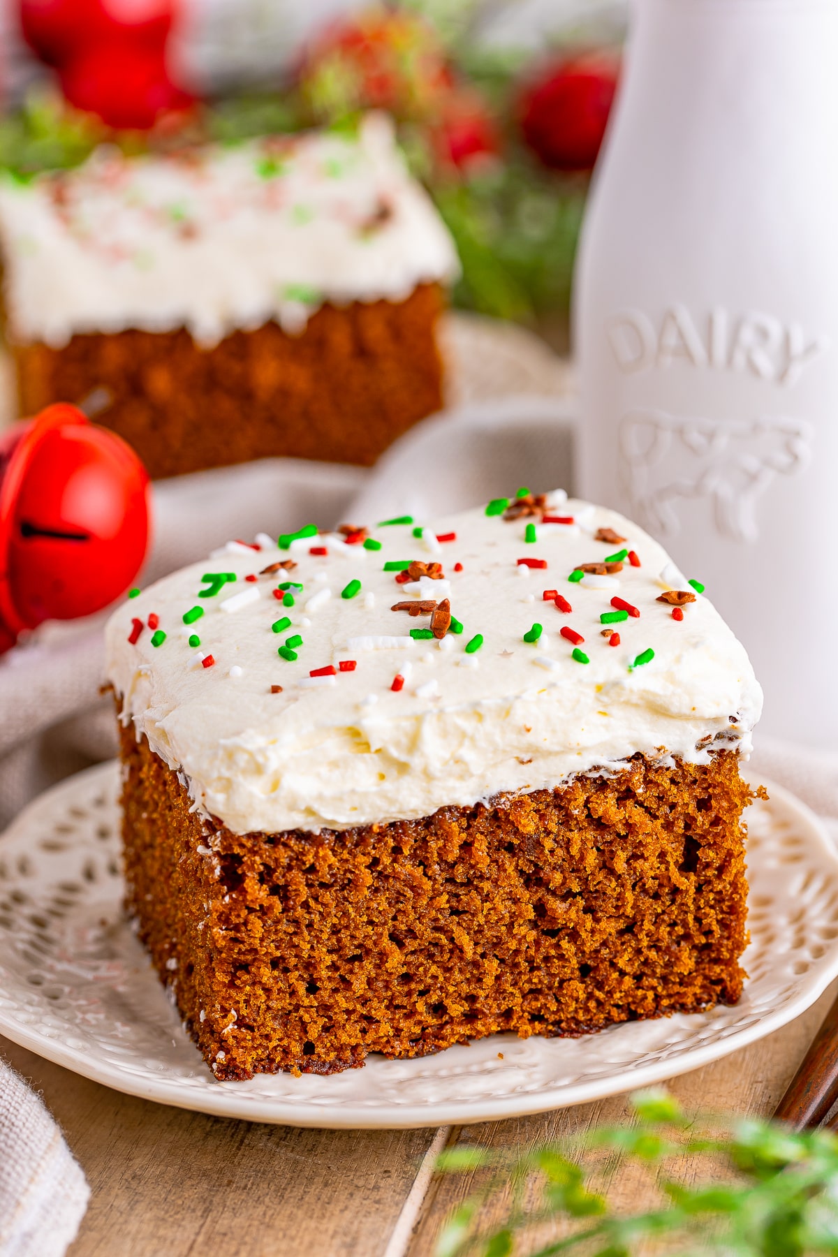 Slice of Gingerbread Cake on white plate topped with sprinkles.