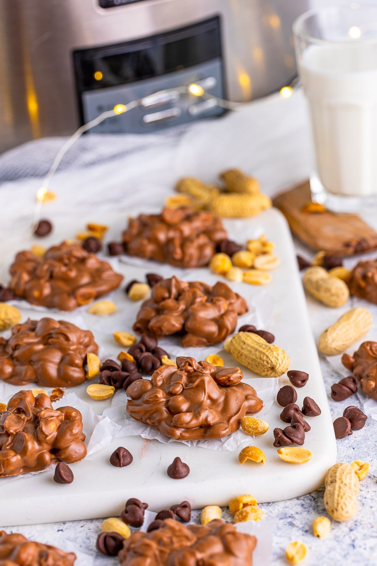 Slow Cooker Peanut Clusters on board with peanuts and chocolate chips surrounding them.