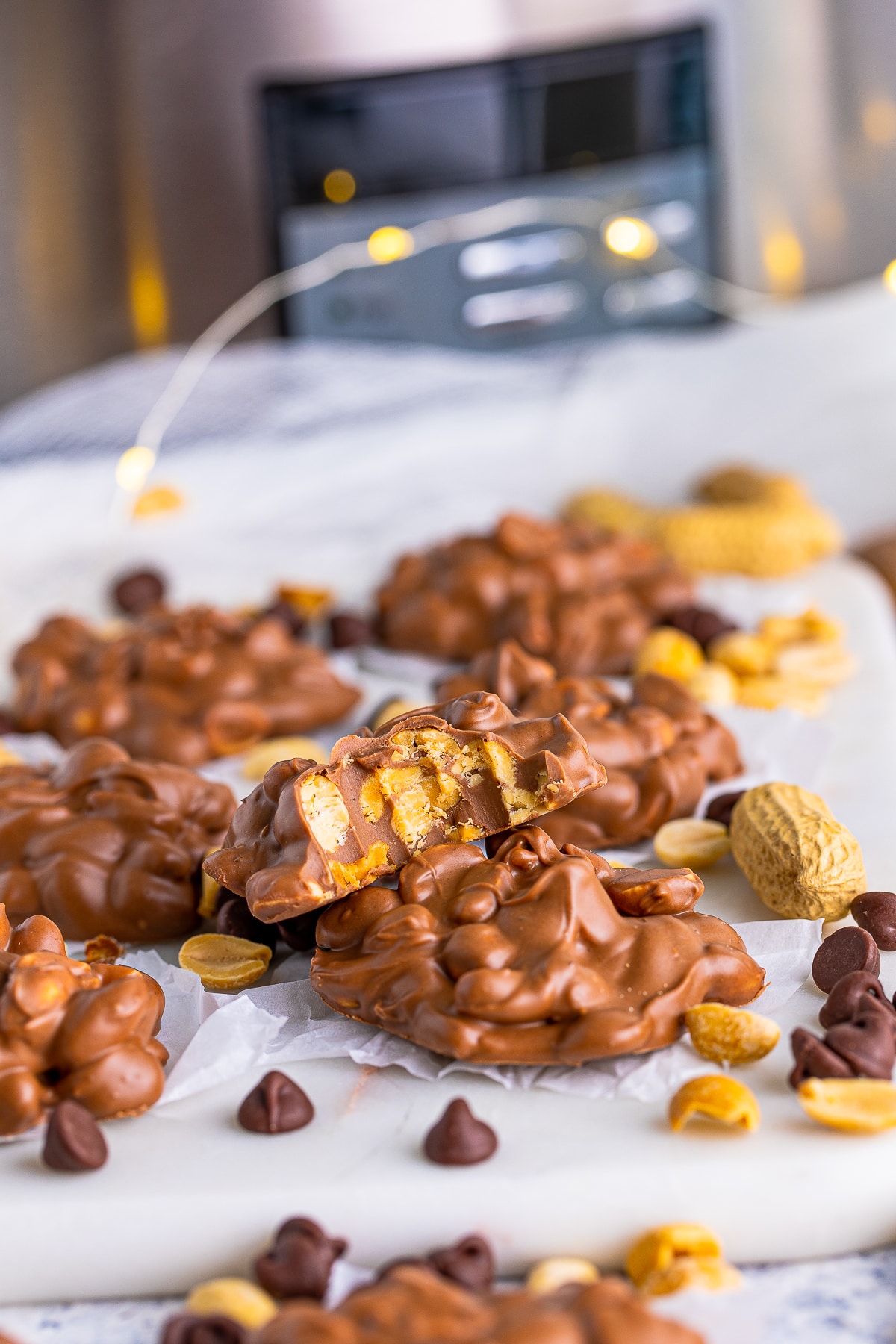 Slow Cooker Peanut Clusters on white board with one stacked with bite taken out of it.