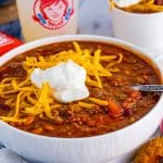 Wendy's Chili in bowl with toppings and spoon.