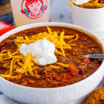 Wendy's Chili in bowl with toppings and spoon.