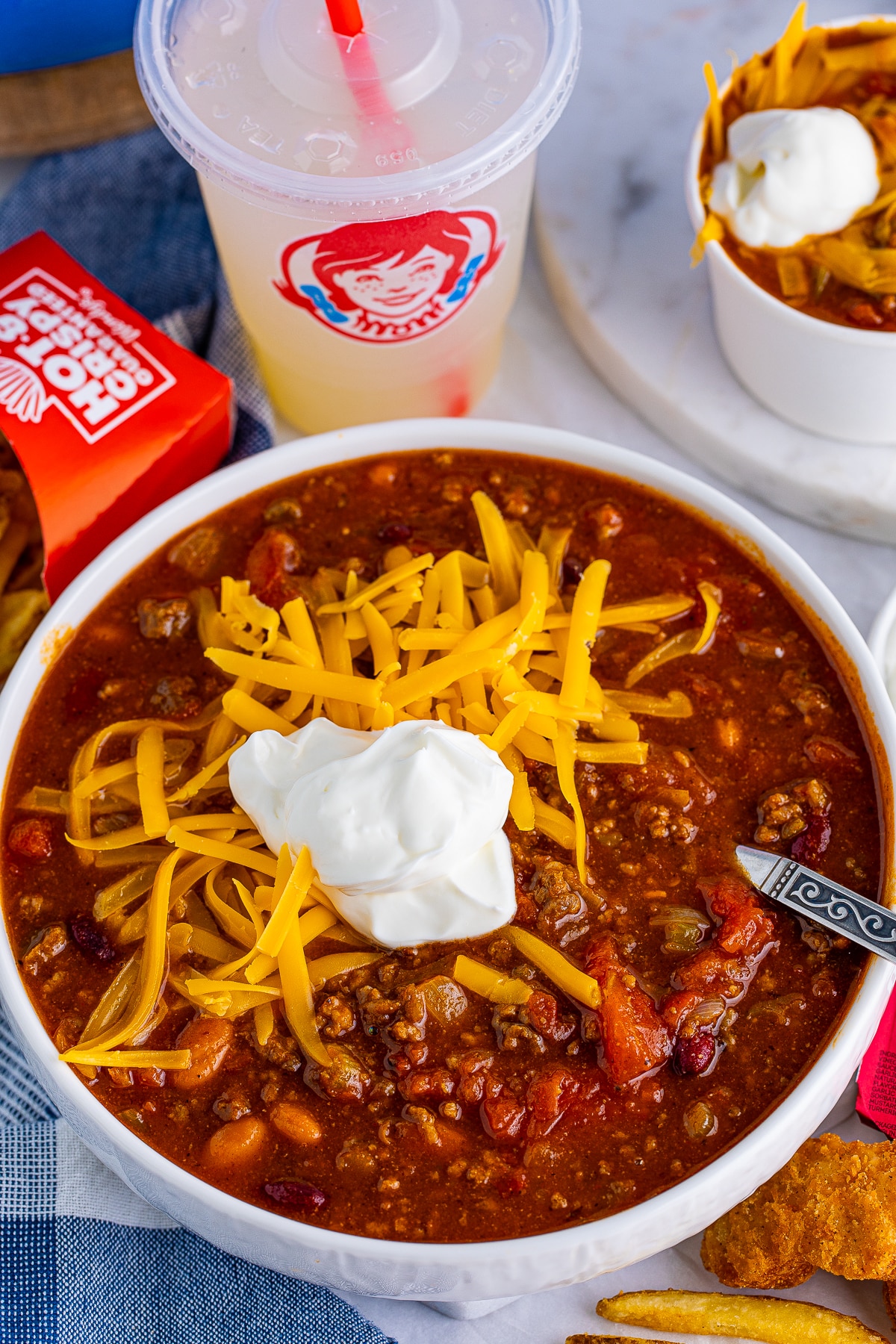 Overhead of bowl of Wendy's Chili with toppings and spoon.