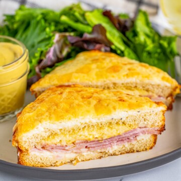 One Croque Monsieur Recipe on plate cut in half with salad.