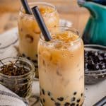 A tall glass of boba tea with tapioca pearls, ice, and a black straw