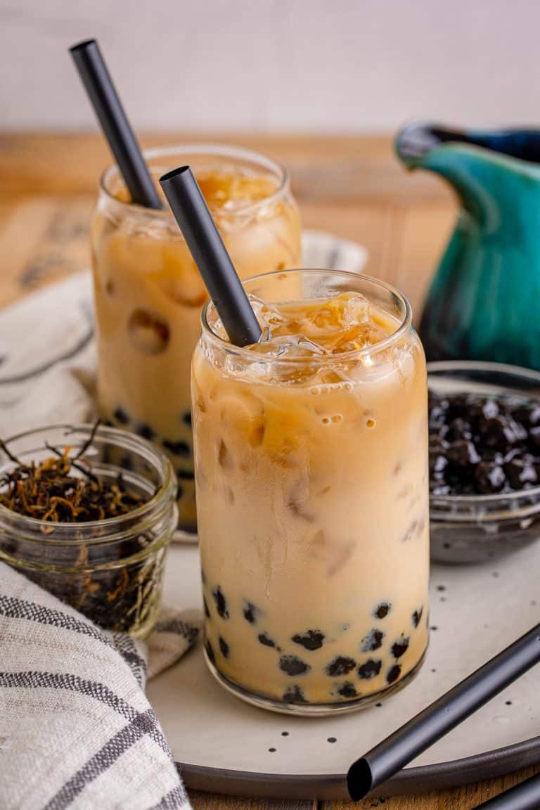 A tall glass of boba tea with tapioca pearls, ice, and a black straw
