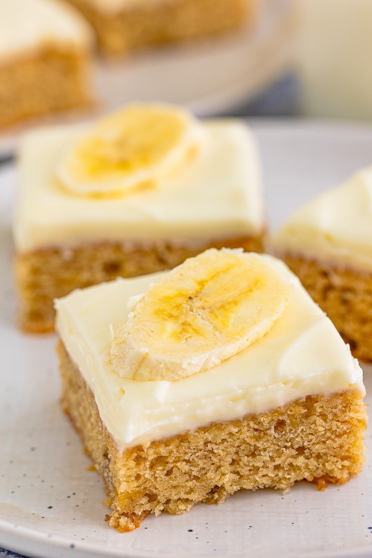 Up close shot of Banana Blondies on white plate with a slice on banana on top.
