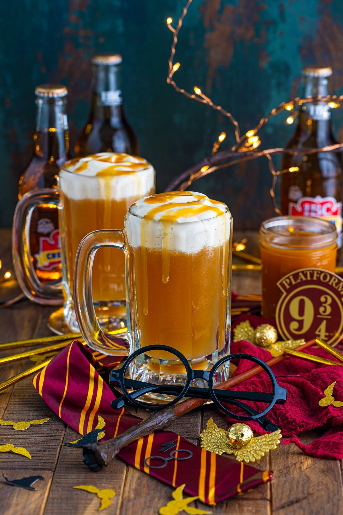 Two glasses of the Butterbeer Recipe surrounded by Harry Potter props.