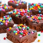 A stack of homemade cosmic brownies topped with chocolate ganache and rainbow candy chips.