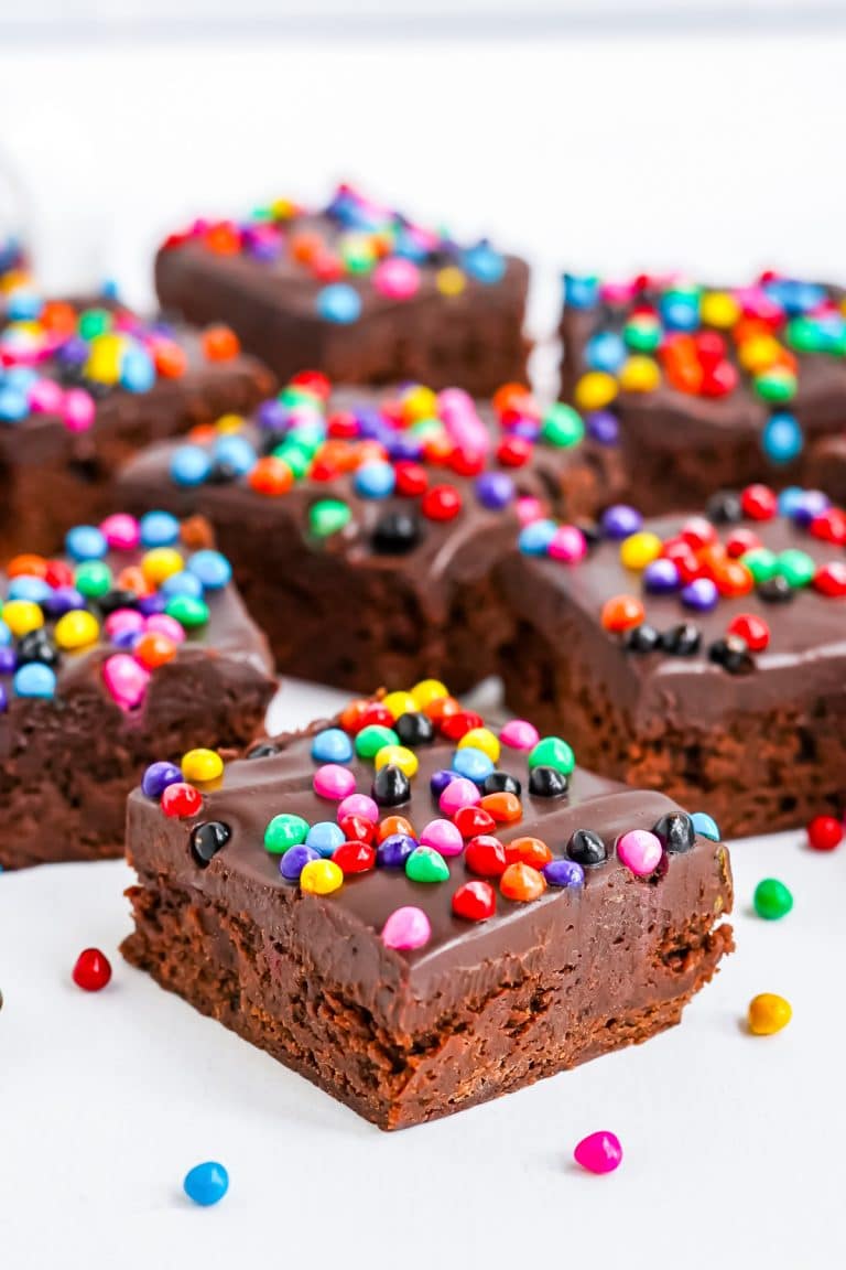 A stack of homemade cosmic brownies topped with chocolate ganache and rainbow candy chips.