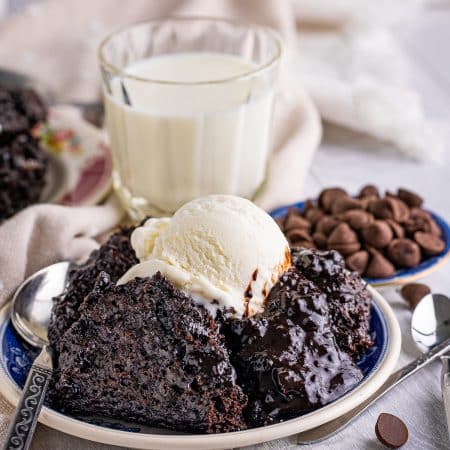 Chocolate Pudding Cake on white plate with ice cream and chocolate chips around it.