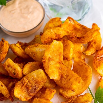 Onion petals served on a white platter with dipping sauce.