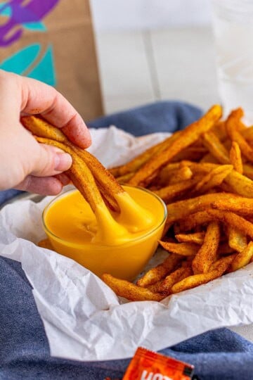 Nacho Fries Recipe being dipped into nacho sauce.