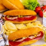 Baked Italian subs loaded with salami, ham, pepperoni, and provolone on toasted hoagie rolls, served with chips.
