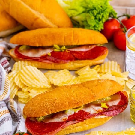 Baked Italian subs loaded with salami, ham, pepperoni, and provolone on toasted hoagie rolls, served with chips.