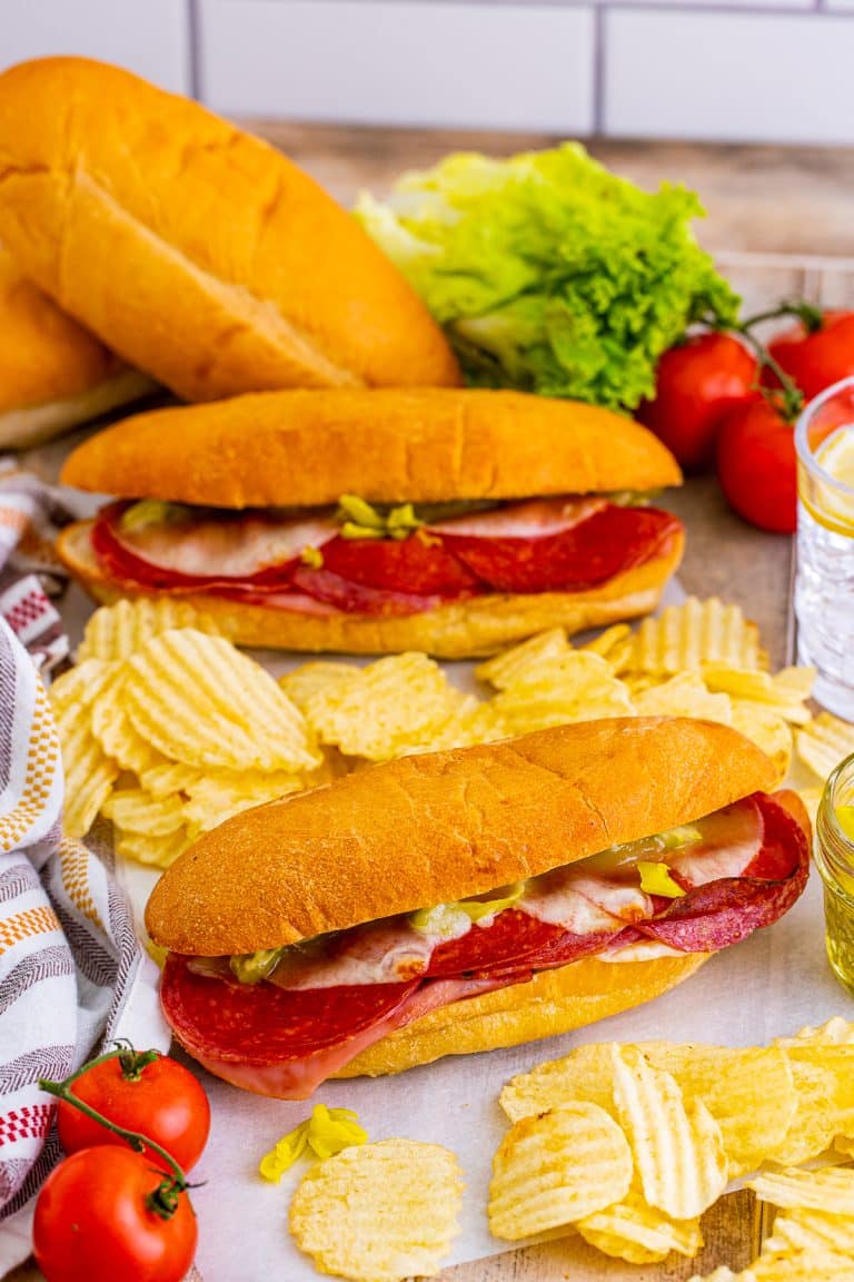 Baked Italian subs loaded with salami, ham, pepperoni, and provolone on toasted hoagie rolls, served with chips.