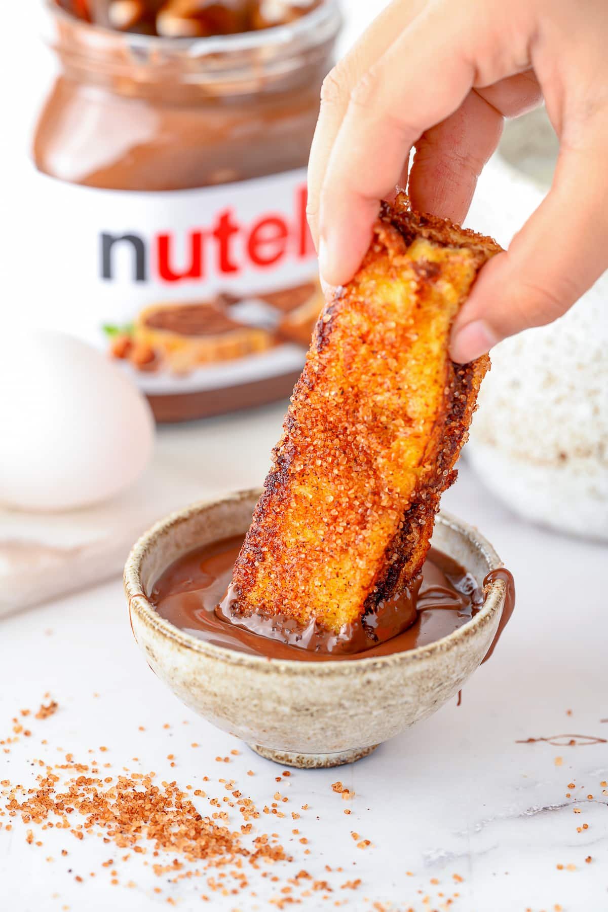 Hand dipping one of the French toast sticks in Nutella.