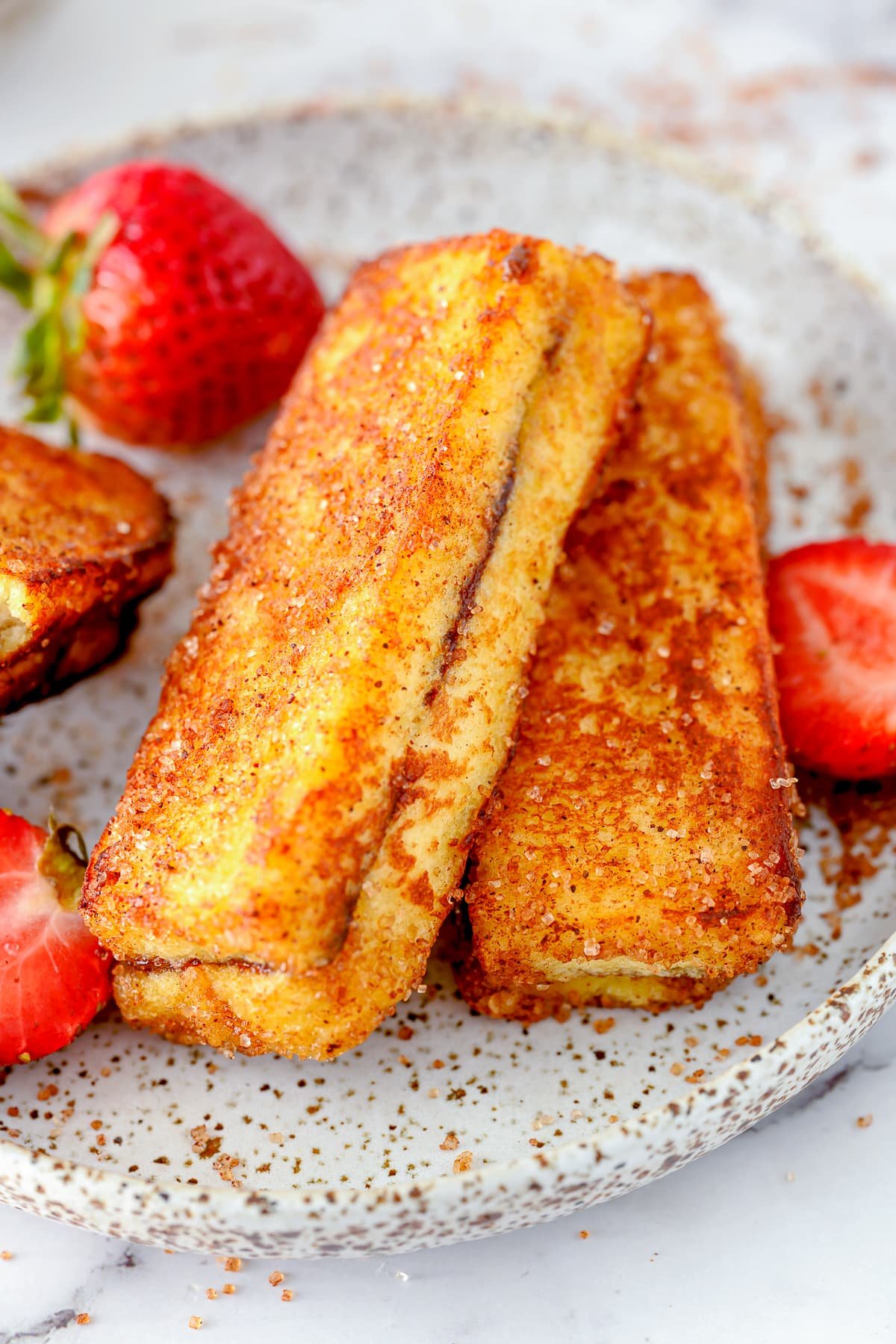 Overhead of two Nutella French Toast Sticks layered on plate with strawberries.