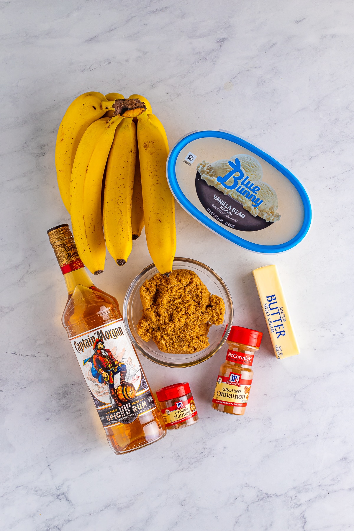 Overhead photo of ingredients needed to make New Orleans Bananas Foster on grey marble countertop