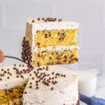 A slice of chocolate chip cake on a plate showing two moist layers full of mini chocolate chips.