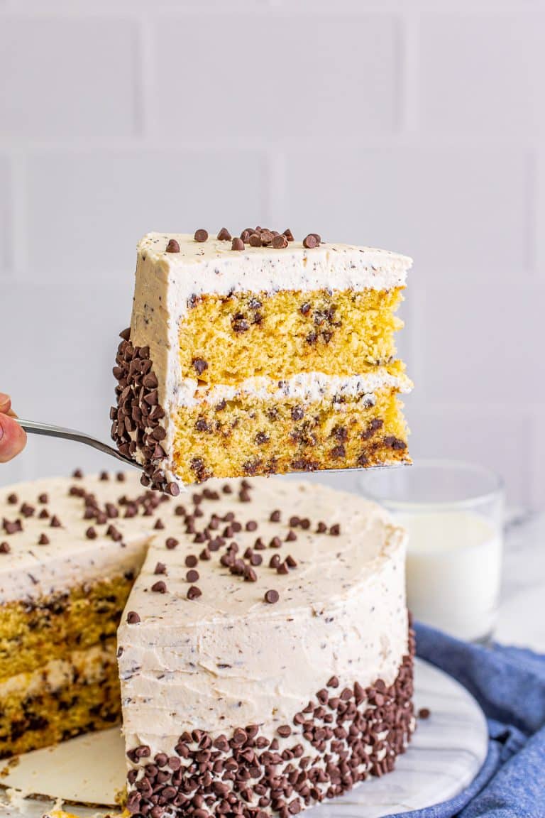 A slice of chocolate chip cake on a plate showing two moist layers full of mini chocolate chips.