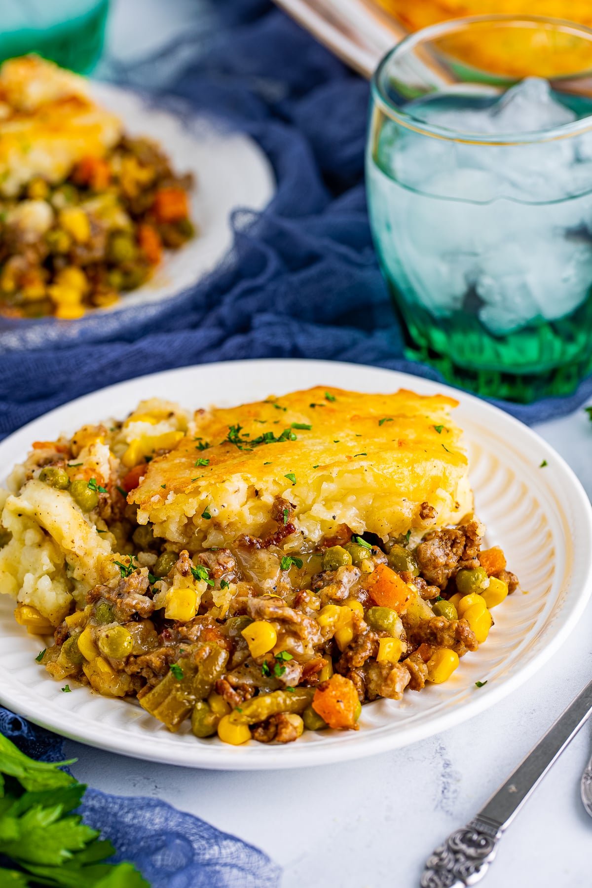 Easy Cottage Pie Recipe served on a white plate with glass of ice water and navy linen