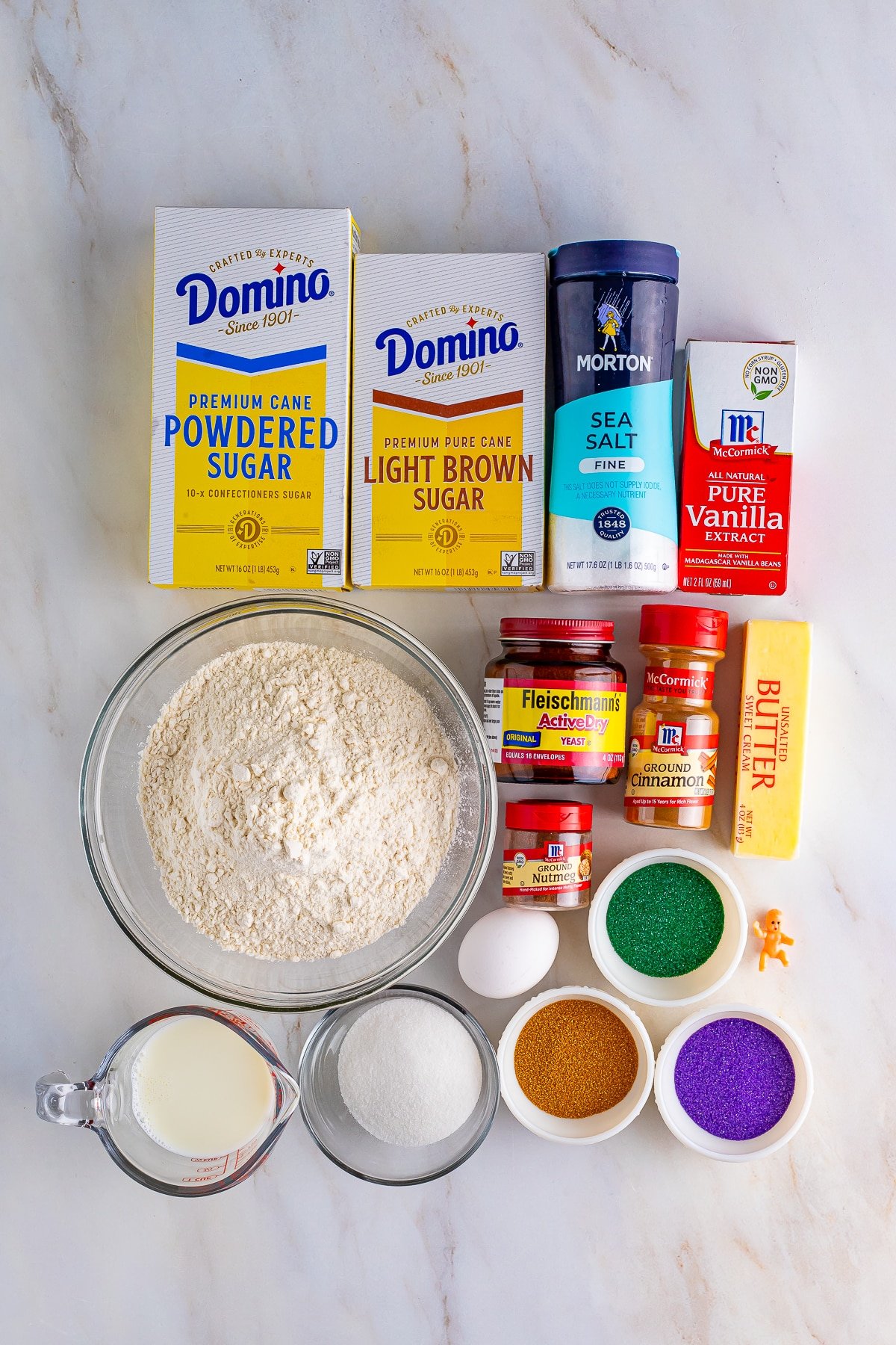 Overhead shot of all the ingredients needs to make this King Cake Recipe laid out on a tan mable table top
