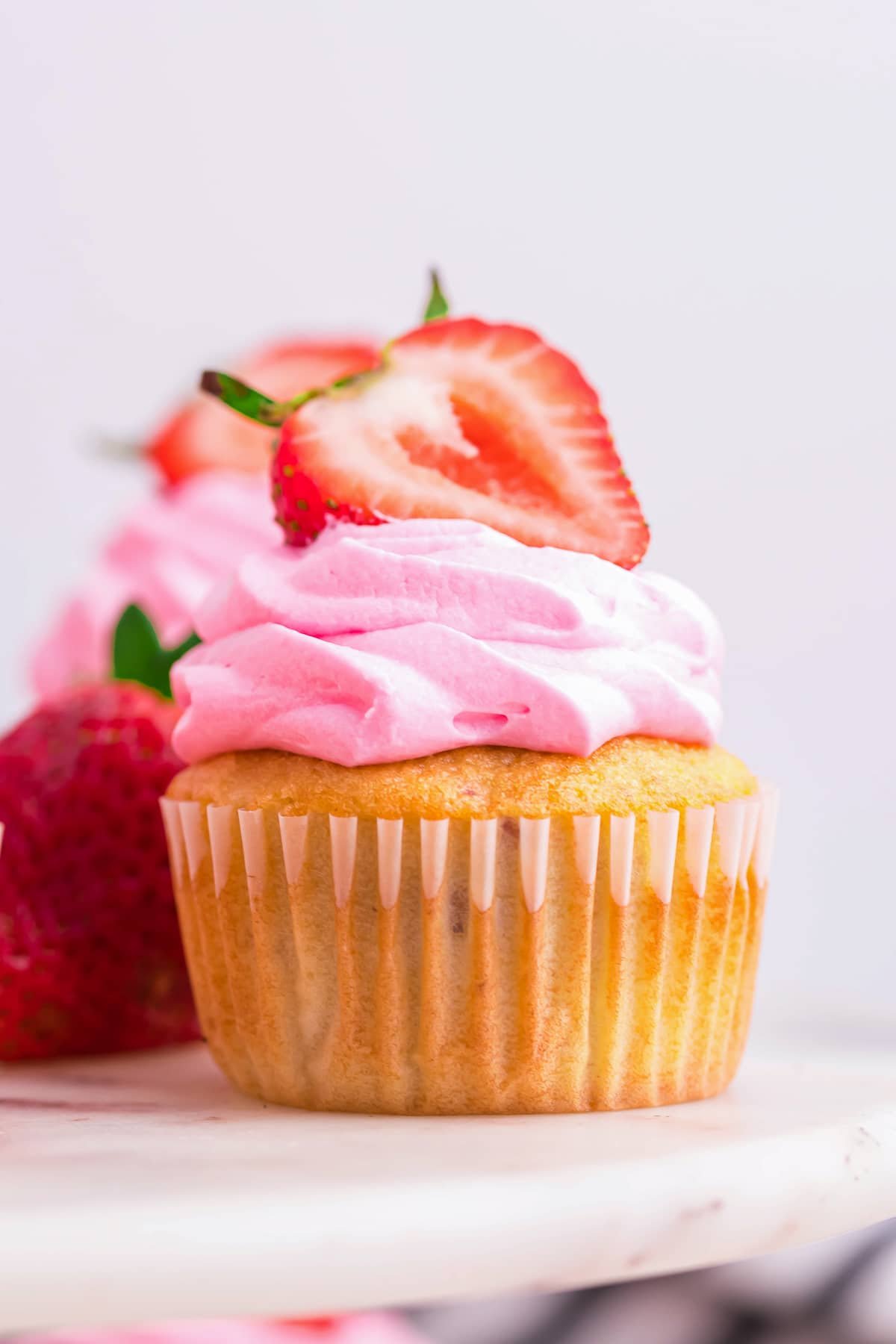 Straight on photo of Strawberry Cupcakes on a white marble cake stand