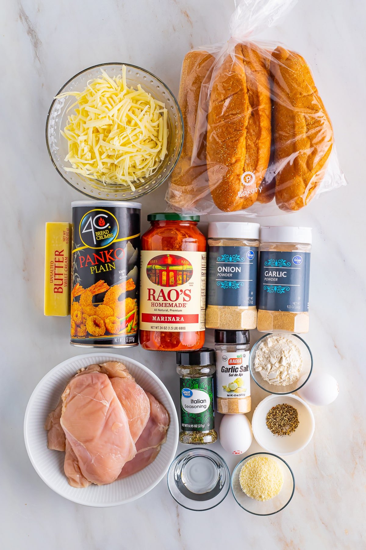 Overhead image of ingredients needed to make Chicken Parmesan Subs Recipe on a tan marble table top