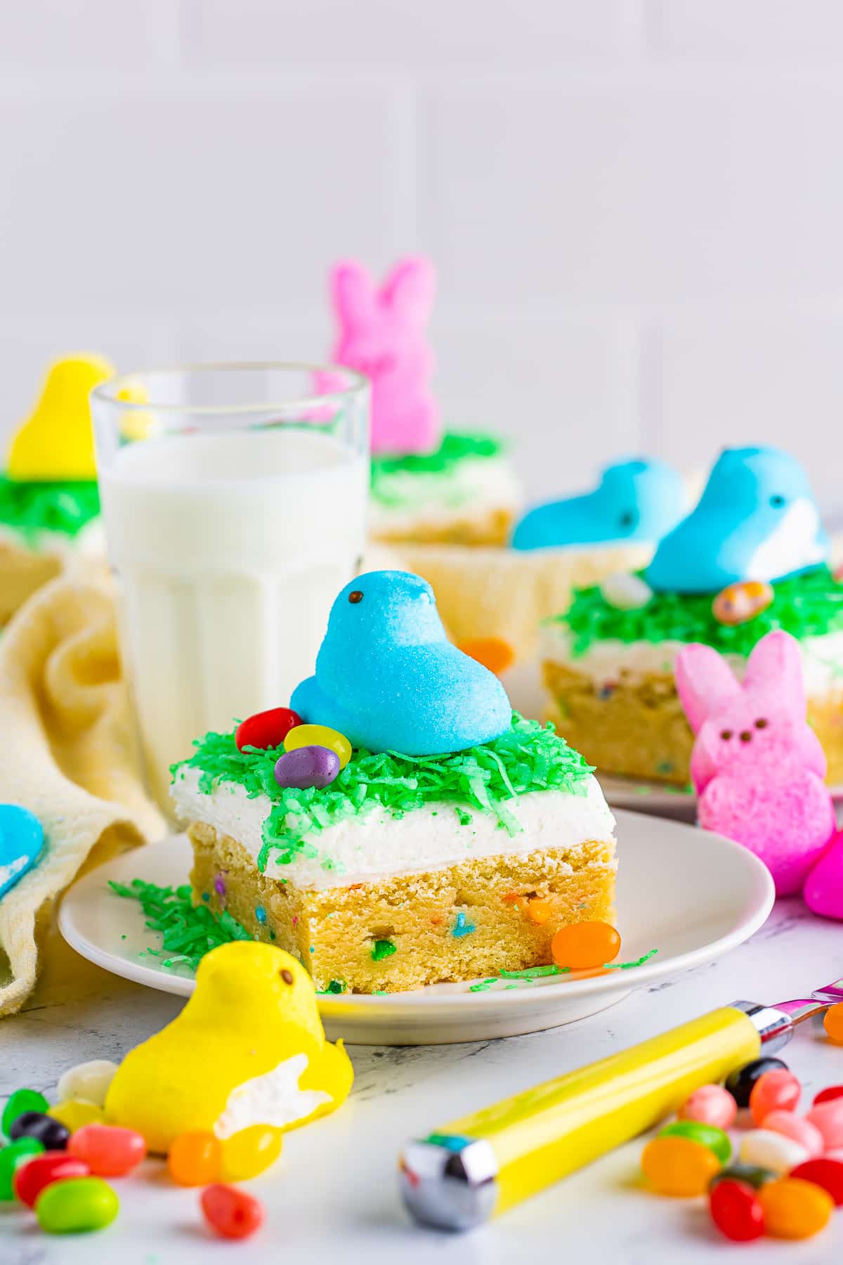 An easter cookie bar on a white plate with yellow linen, yellow fork, and lots of colorful easter peeps
