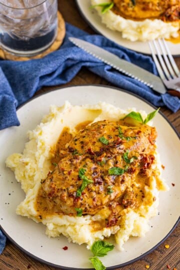 Marry Me Chicken served over creamy mashed potatoes with sundried tomato cream sauce and fresh basil.