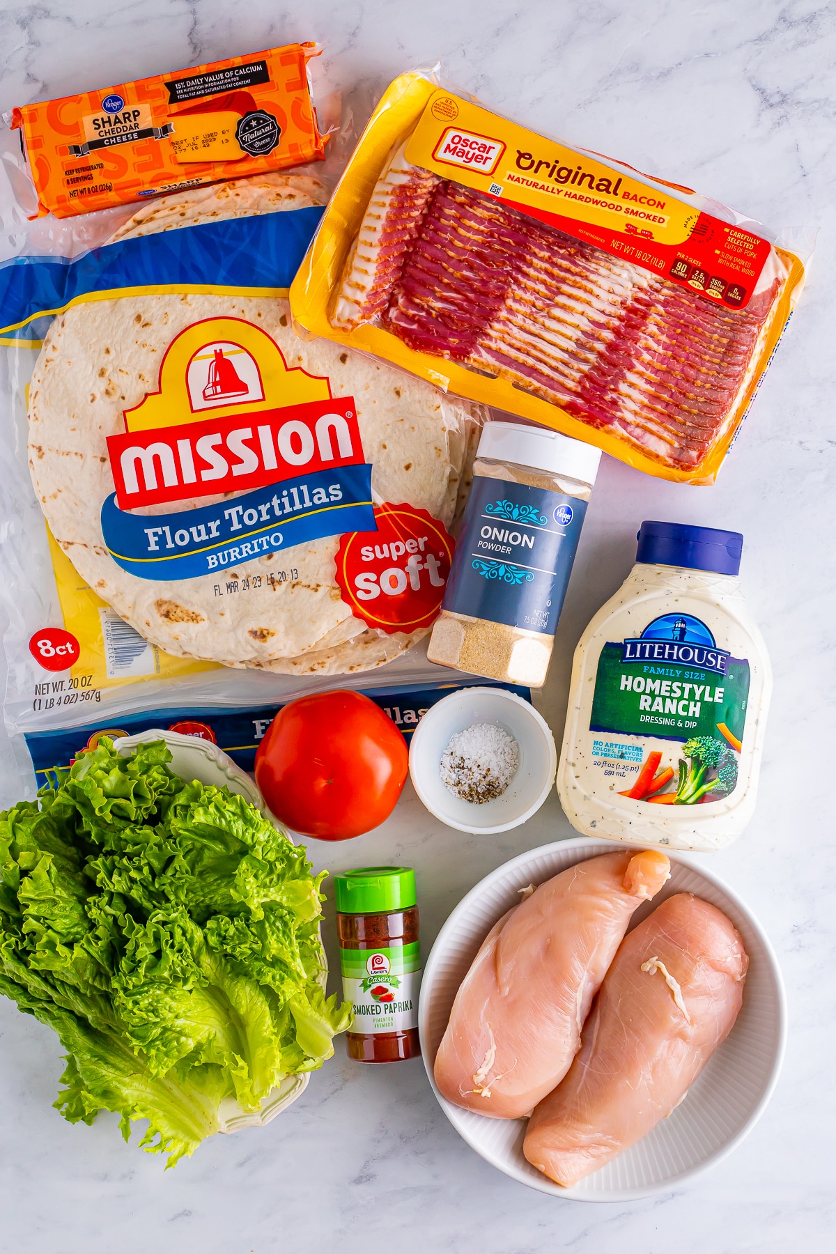 Overhead image showing the ingredients needed to make bacon ranch chicken wrap on a grey marble table top