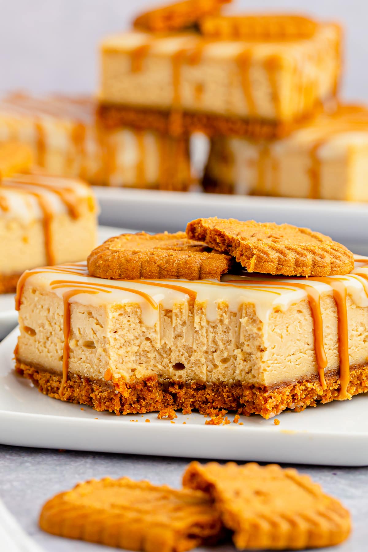 Interior photos of one of the Biscoff Cheesecake Bars on a white plate, more cheesecake bars in the background